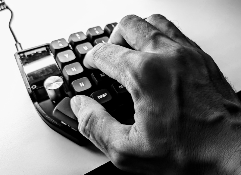 Hand on split keyboard in black and white